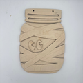 A light natural wood decorative plaque or board with geometric cutout patterns and a stylized face design, photographed against a plain white background.