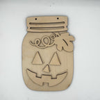 A laser-cut wooden jack-o'-lantern wall hanging shaped like a mason jar, shown on a plain white background.
