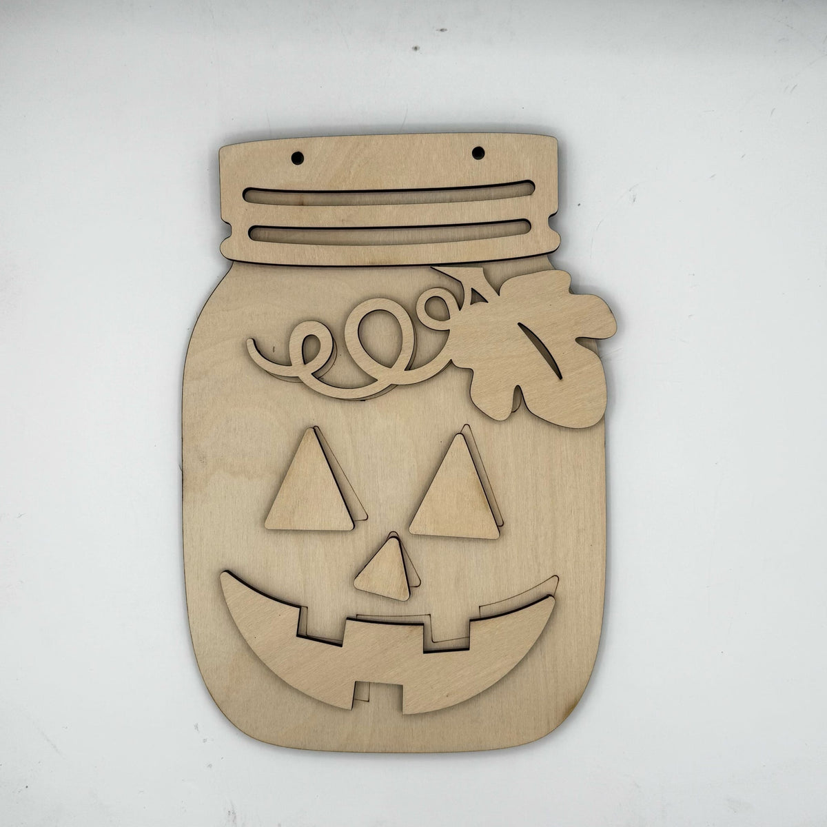 A laser-cut wooden jack-o'-lantern wall hanging shaped like a mason jar, shown on a plain white background.
