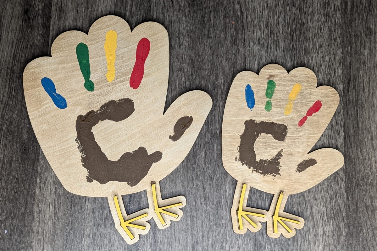Two wooden hand-shaped cutouts with painted fingers and feet on a dark wooden surface.