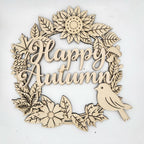 A laser-cut wooden decorative sign featuring the words 'Happy Autumn' in cursive script, surrounded by autumn leaves, flowers, a pinecone, and a small bird, shown on a plain white background.