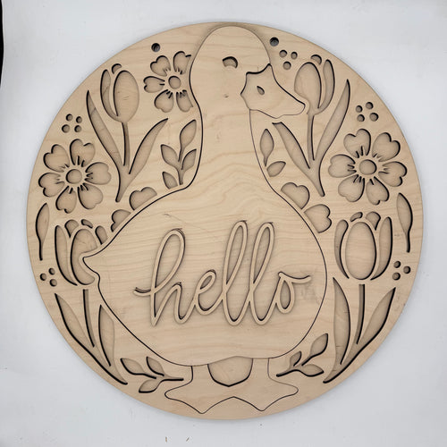 A round, laser-cut wooden wall sign featuring a duck silhouette with the word 'hello' cut into the center, surrounded by tulips and flowers. The natural wood grain is clearly visible against a plain white background.