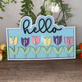 A decorative tulip sign with the words 'Hello Spring' in a circular frame, surrounded by artificial tulips in various colors.