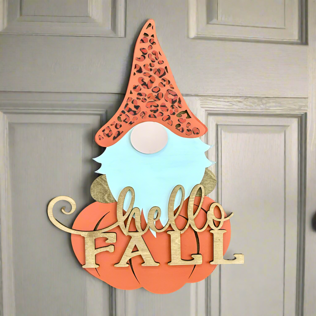 Decorative sign with a gnome face and 'hello FALL' text on a gray door.