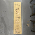 Wooden plaque with engraved designs and text on a gray surface