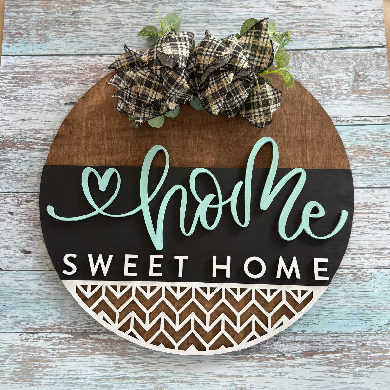 Decorative sign with 'home sweet home' text and plaid bow on a wooden background