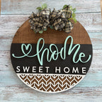 Decorative sign with 'home sweet home' text and plaid bow on a wooden background