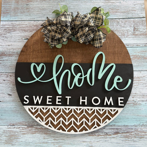 Decorative sign with 'home sweet home' text and plaid bow on a wooden background