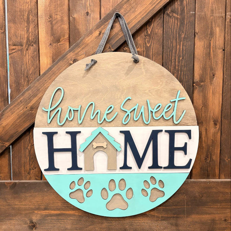 Decorative sign with 'home sweet home' text and paw prints on a wooden background