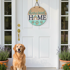 Dog sitting on a doormat in front of a white door with a 'Home Sweet Home' sign.