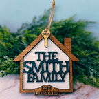 Decorative house-shaped ornament with 'The Smith Family' and address on a marble surface with greenery in the background.