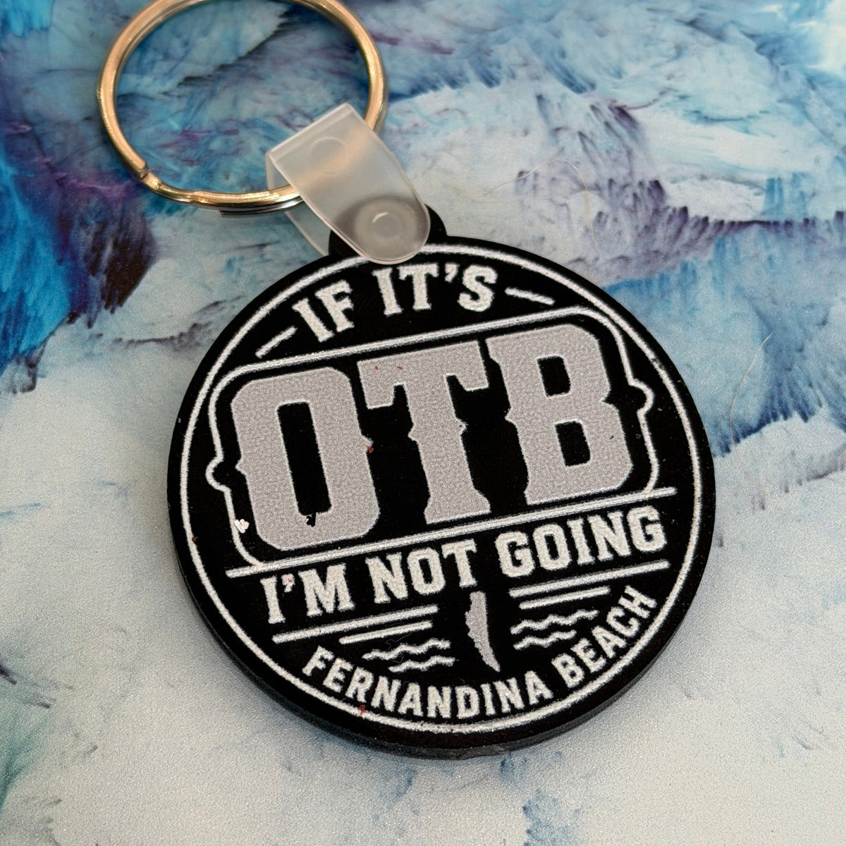Black and white keychain with text on a textured blue and white background