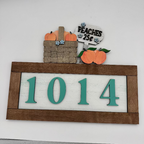 Decorative house number sign with peaches and a basket on a white background