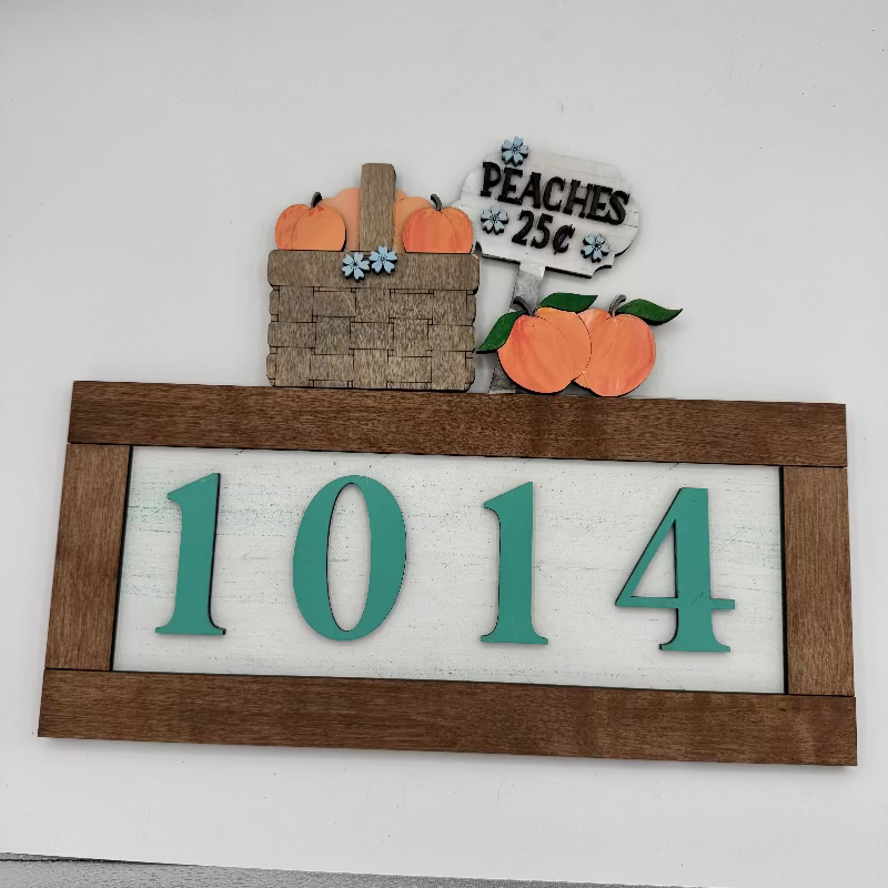 Decorative house number sign with peaches and a basket on a white background