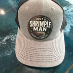 Gray cap with 'Just a Shrimple Man' logo on a reflective surface