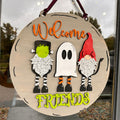 A 3D door hanger featuring two gnomes and a ghost with the text 'Welcome Friends' on a round wooden board.