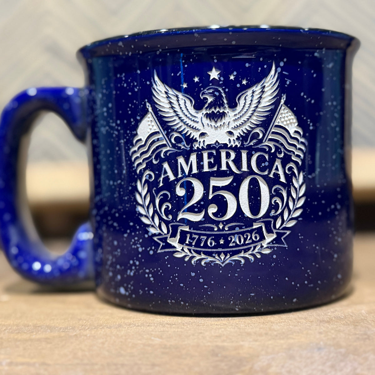 Blue mug with white eagle design and 'America 250' text on a wooden surface.
