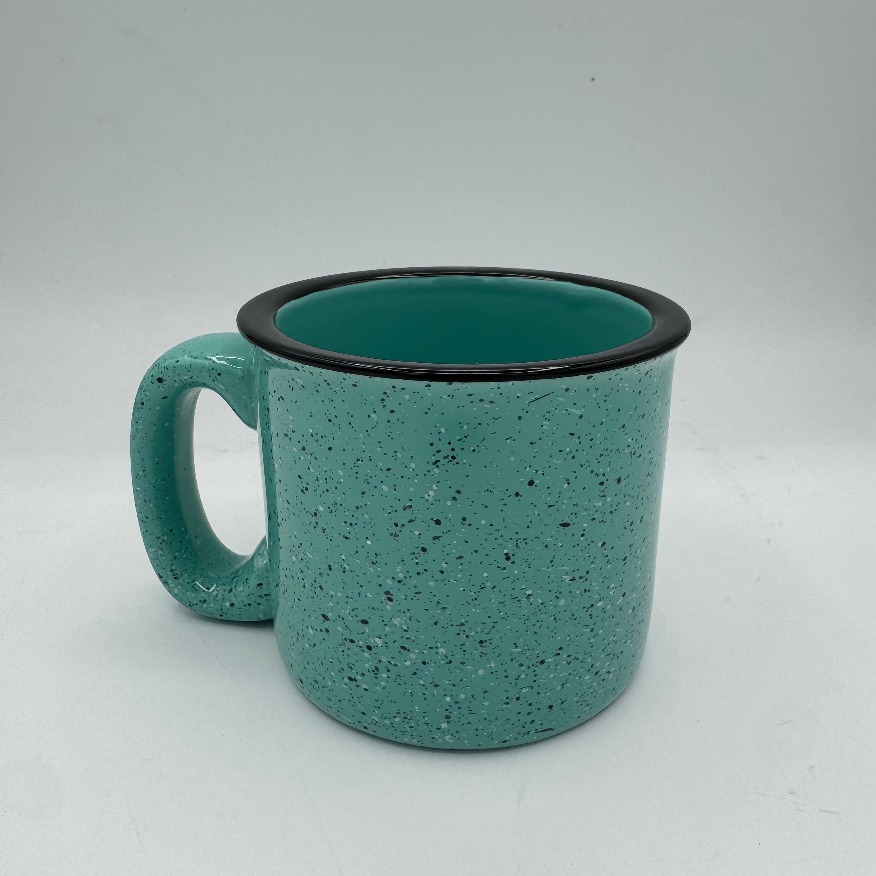 Teal speckled mug with black rim on a light gray background