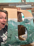 Wooden letter B finished with a teal and white epoxy ocean pour