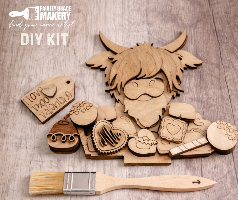 Wooden DIY kit with laser-cut pieces and a paintbrush on a wooden surface, featuring Paisley Grace Design branding.