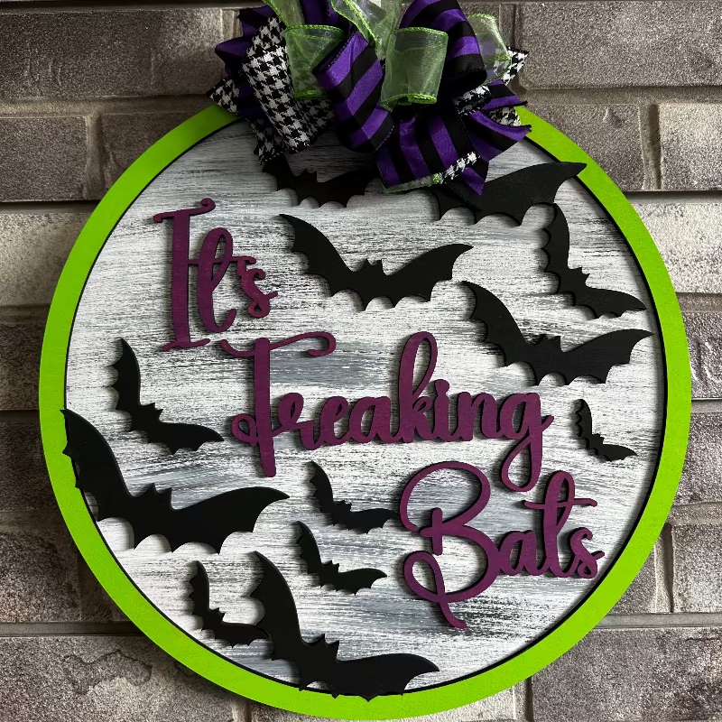 3D door hanger with a green background and bats in black, white text that reads 'It's Freaking Bats'.