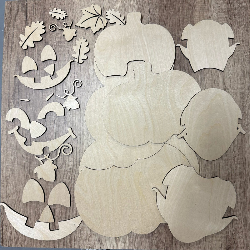 Wooden cutouts of pumpkins and leaves on a wooden background