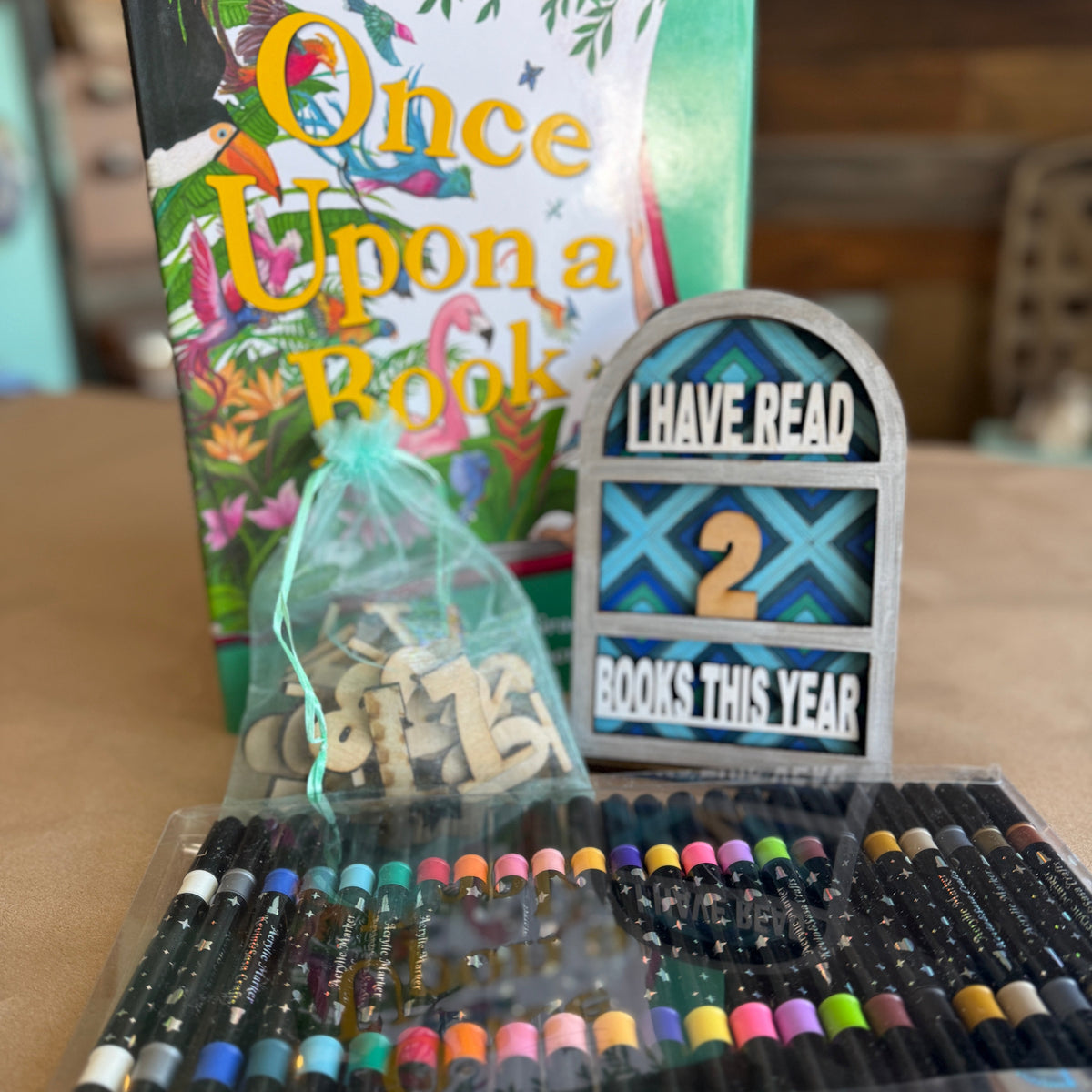 Stationery items including pens, a book titled 'Once Upon a Book', and a decorative sign on a table.