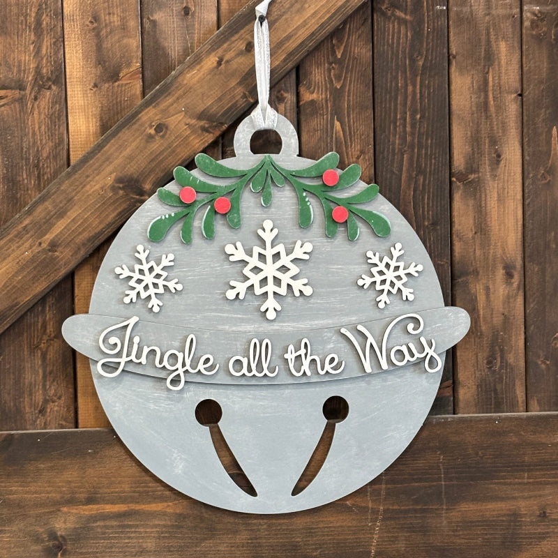 Decorative Christmas bell sign with 'Jingle all the Way' text on a wooden background