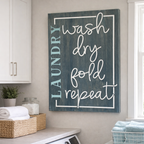 Laundry room with a sign that reads 'LAUNDRY wash dry fold repeat' on a wall above a washer and dryer.