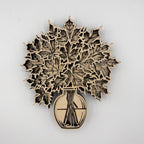 Laser-cut wooden wall art featuring layered maple leaves in a vase, shown against a plain light gray background.