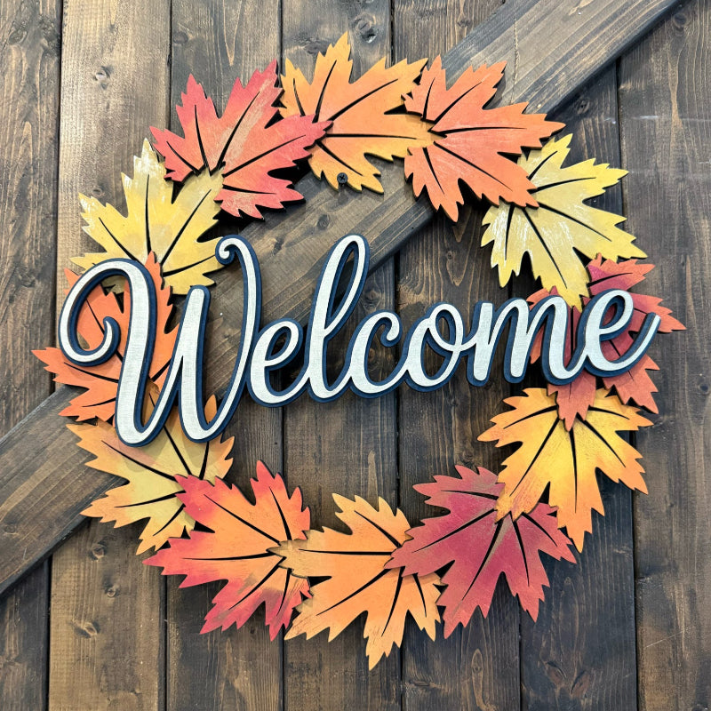 Decorative wreath with autumn leaves and 'Welcome' text on a wooden background