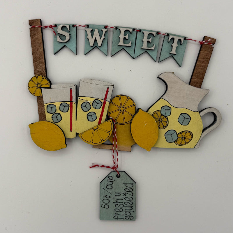Decorative sign with lemonade cups, lemons, and a 'Sweet' banner on a white background.
