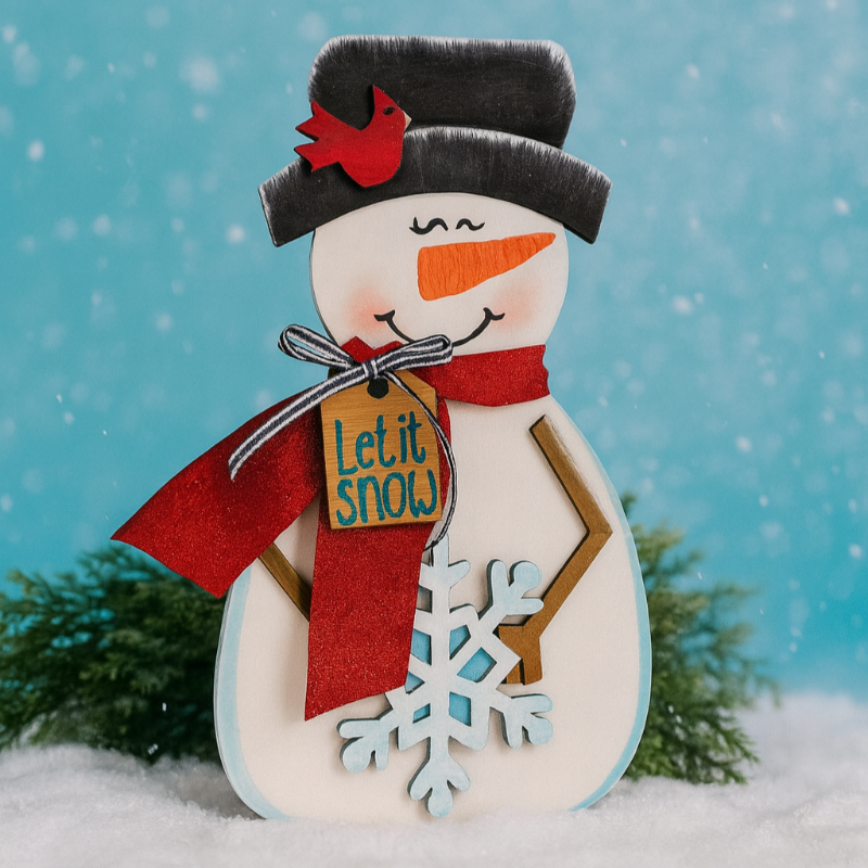 Decorative snowman figurine with a red scarf and 'Let it snow' sign against a snowy background.