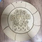 Wooden circular sign with 'Life's Better at the Pool' text on a wooden surface
