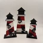 Set of three decorative lighthouse figures with red, white, and black design on a white background