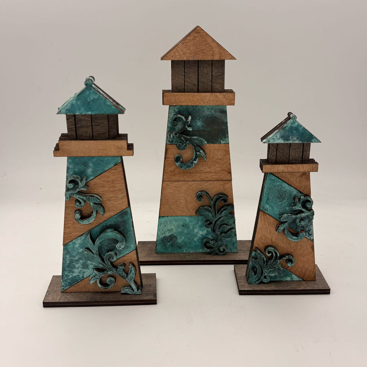 Set of three decorative lighthouse models with turquoise and brown design on a white background