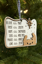 Decorative Christmas ornament with religious text and figures on a green tree.