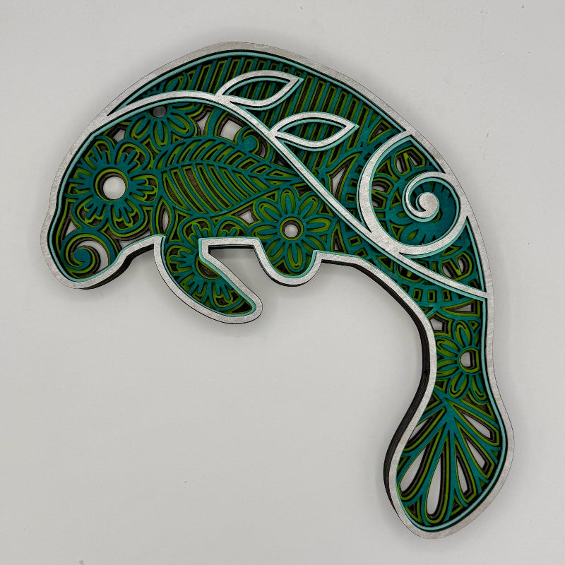 Decorative keychain with intricate green and blue patterns on a white background