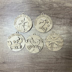 Set of five Christmas-themed metal ornaments on a wooden surface