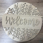 Decorative wooden sign with 'Welcome' text and leaf patterns on a wooden surface