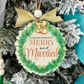 Christmas ornament with 'Merry and Married' text and rings, hanging on a decorated tree. Fernandina Beach Custom Ornaments
