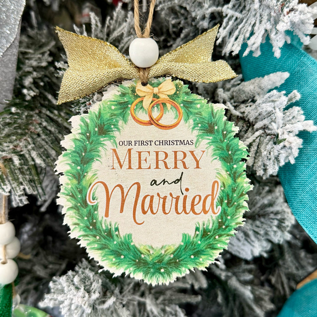 Christmas ornament with 'Merry and Married' text and rings, hanging on a decorated tree. Fernandina Beach Custom Ornaments