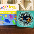 A craft kit depicting an ocean theme with colorful cut-outs of sea creatures, placed next to a colorful book with text and illustrations on the cover.