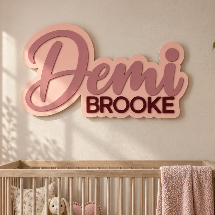 Layered first and middle name nursery sign in blush pink and berry hung above a crib