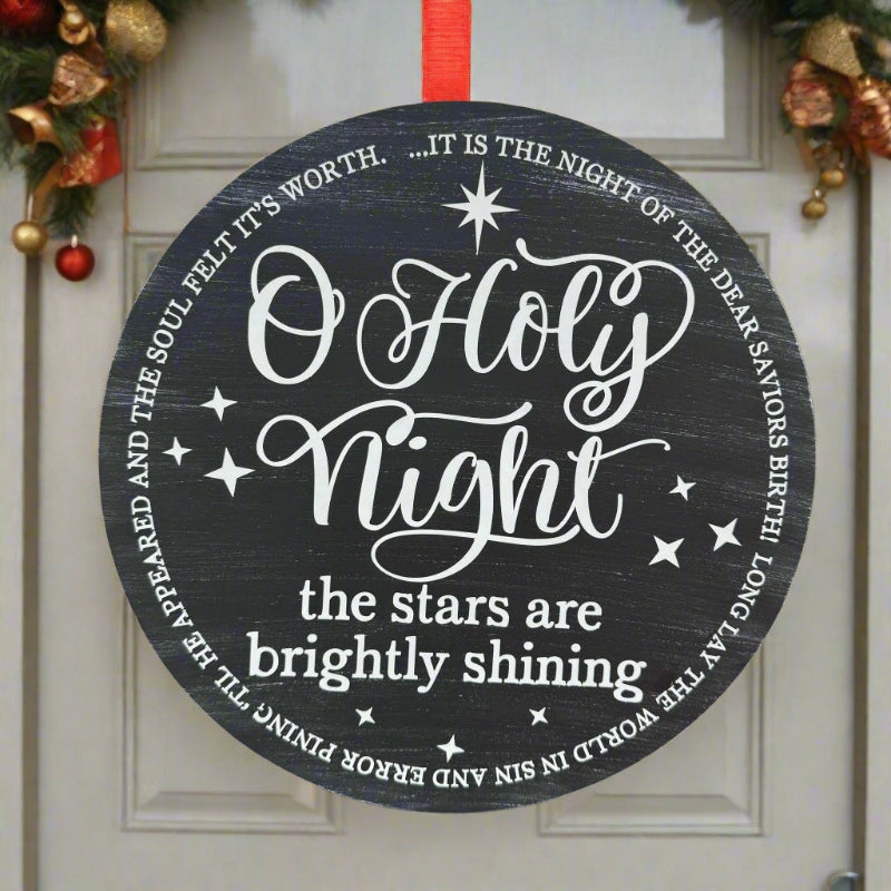 Decorative sign with 'O Holy Night' text hanging on a glass door.