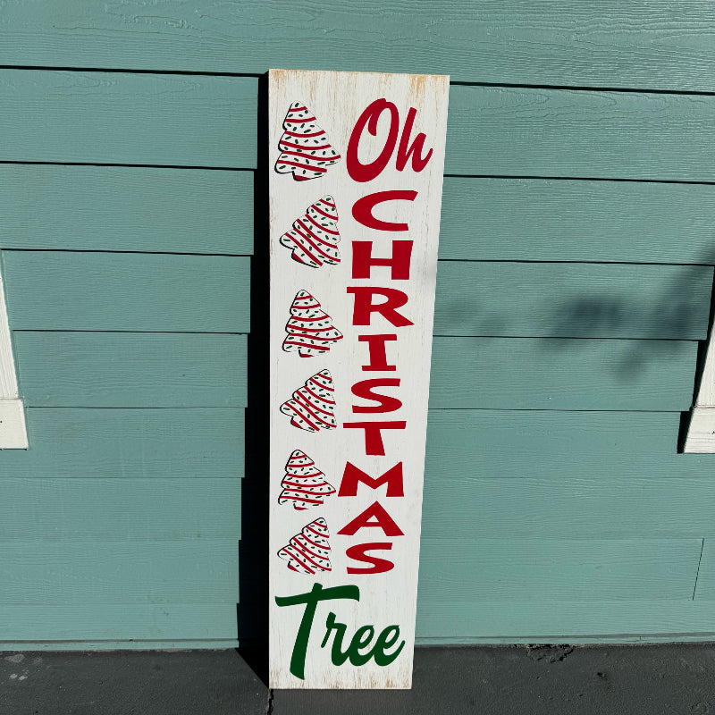 Wooden Christmas sign with 'Oh Christmas Tree' text and tree illustrations against a teal wooden background.