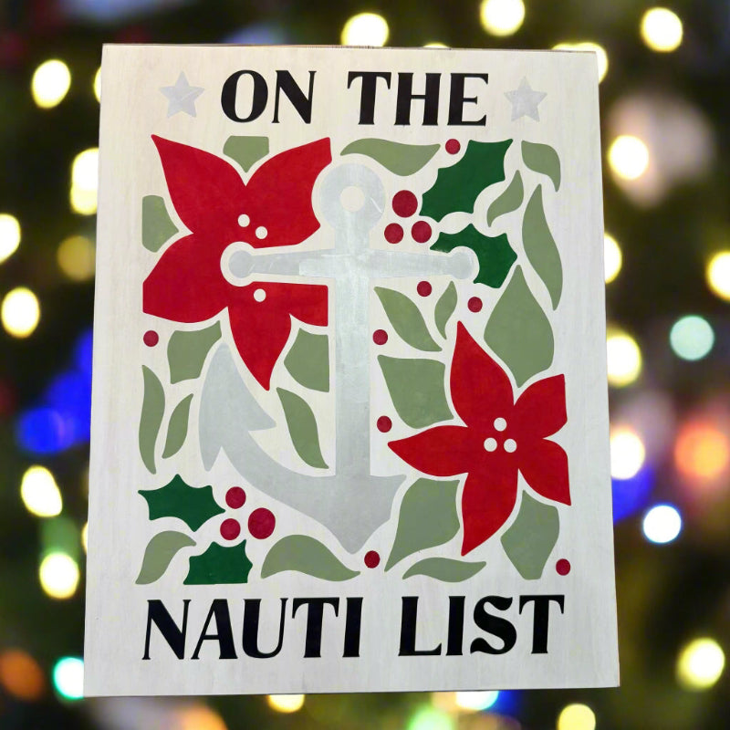 Decorative sign with anchor, flowers, and holly leaves on a wooden background