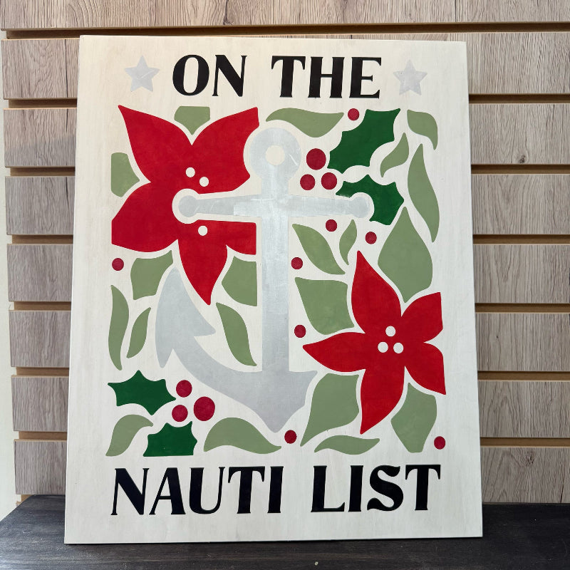 Decorative sign with anchor, flowers, and holly leaves on a wooden background