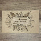 Wooden plaque with 'Our Home est. 2025' engraving on a wooden background