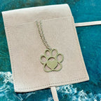 Necklace with a paw print pendant on a beige card against a blue textured background